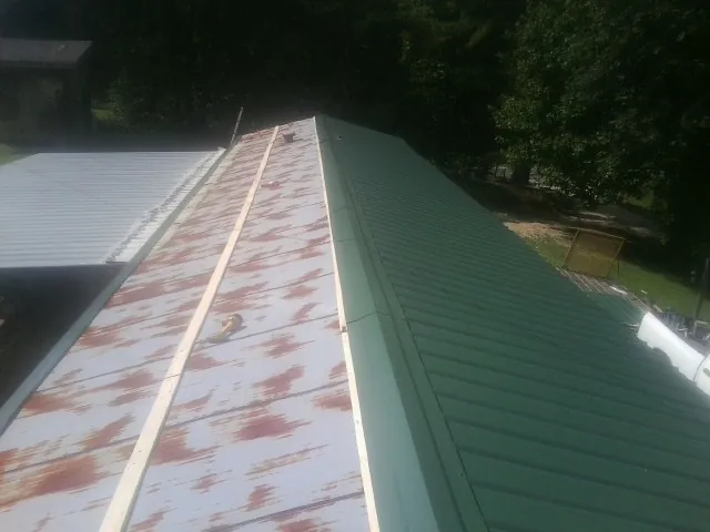 Old rusted panels beside newly installed green metal roofing — Wind Damage Roof Repair by Roofing Brothers in Hailey