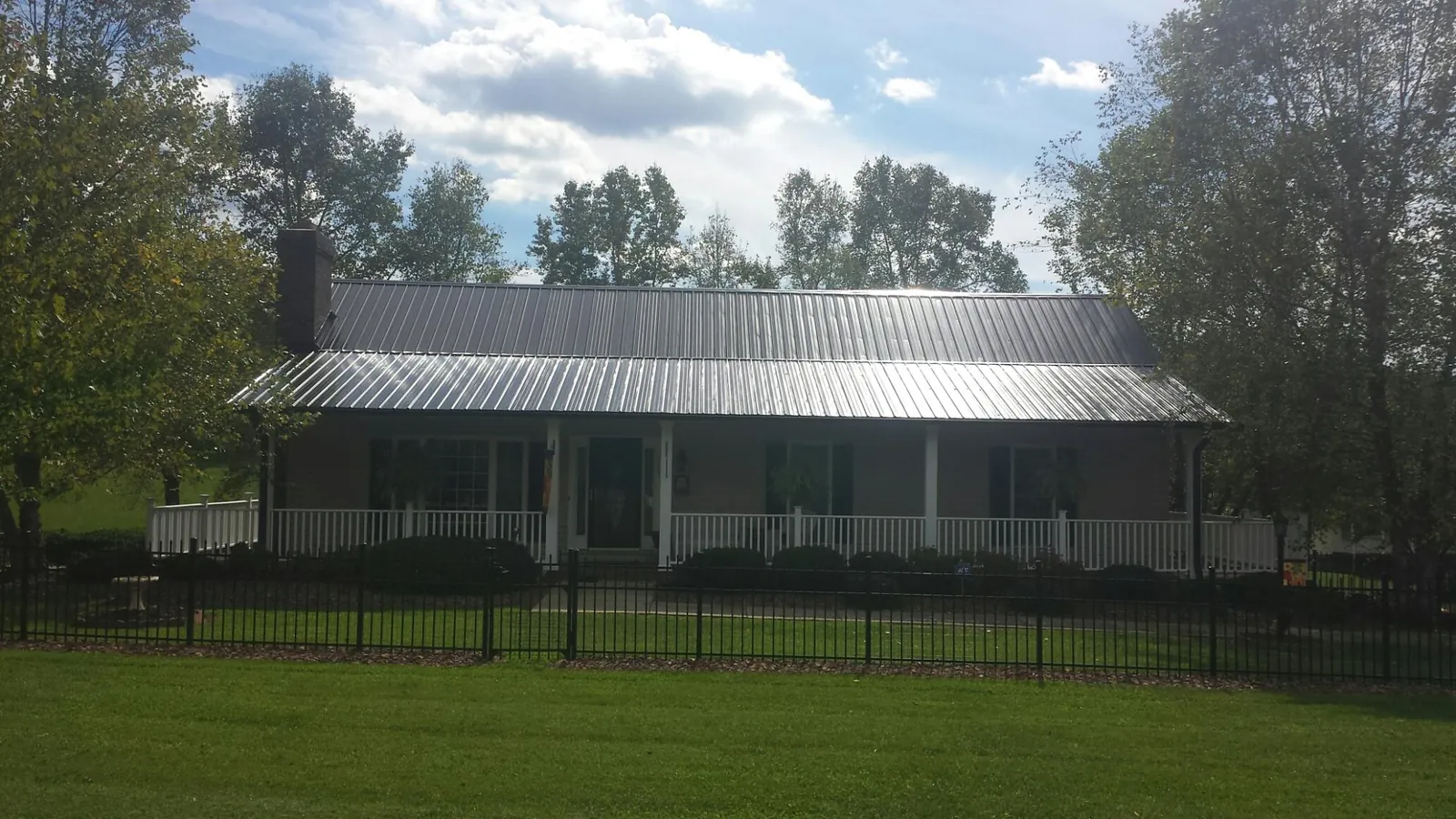 Gray metal roof on a brick ranch with a full width front porch — Gutter Guard Installation work by our crew in Hailey