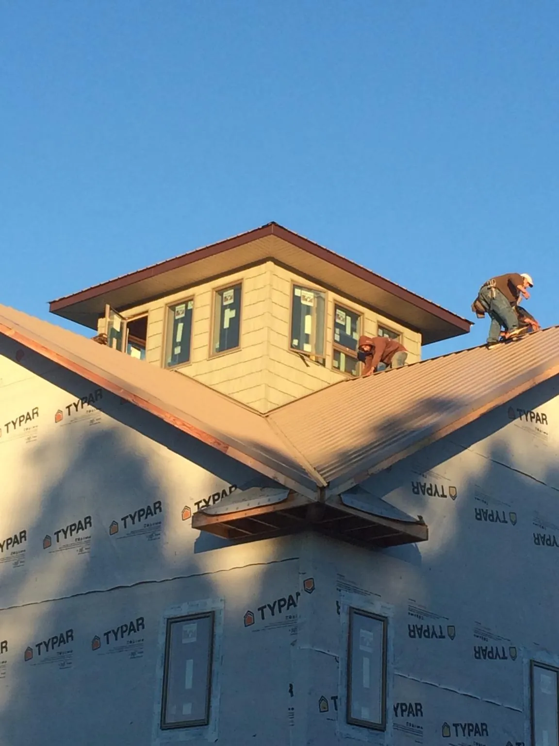 Roofers working around a rooftop cupola on a new metal roof at sunset — Roof Waterproofing in Hailey by Roofing Brothers